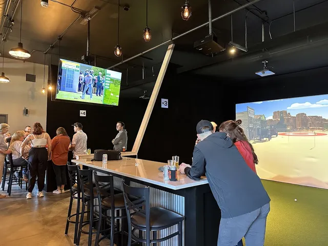 Full view of multiple golf simulator bays and customers at The Bogey Factory